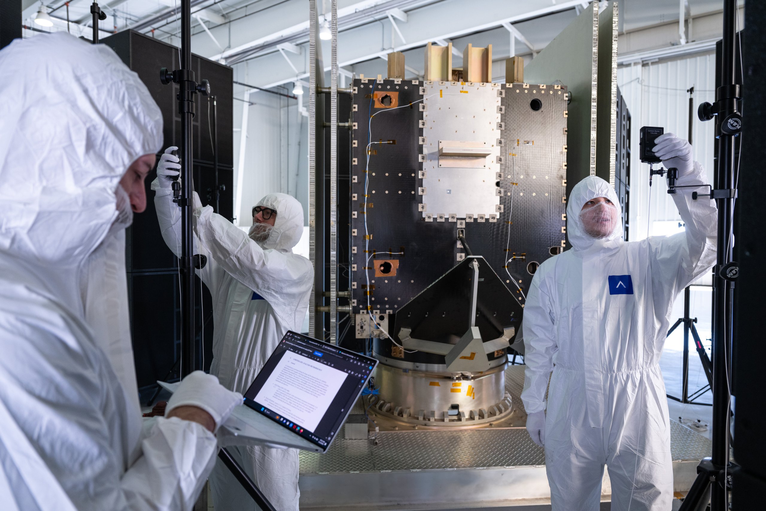 ARS engineers in cleanroom suits instrumenting a spacecraft panel for acoustic testing